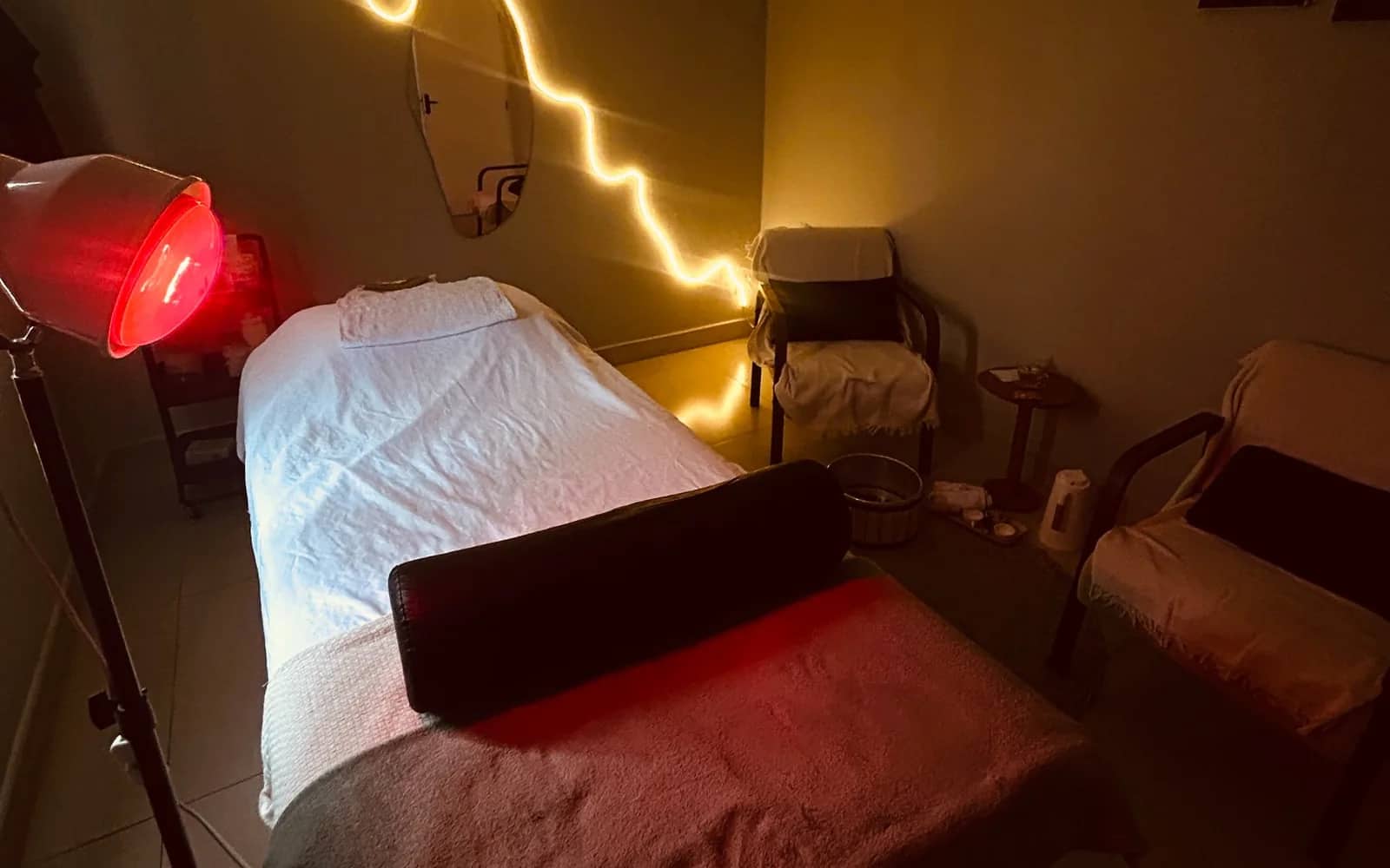 Sala de atendimento com maca, iluminação âmbar e luz vermelha terapêutica